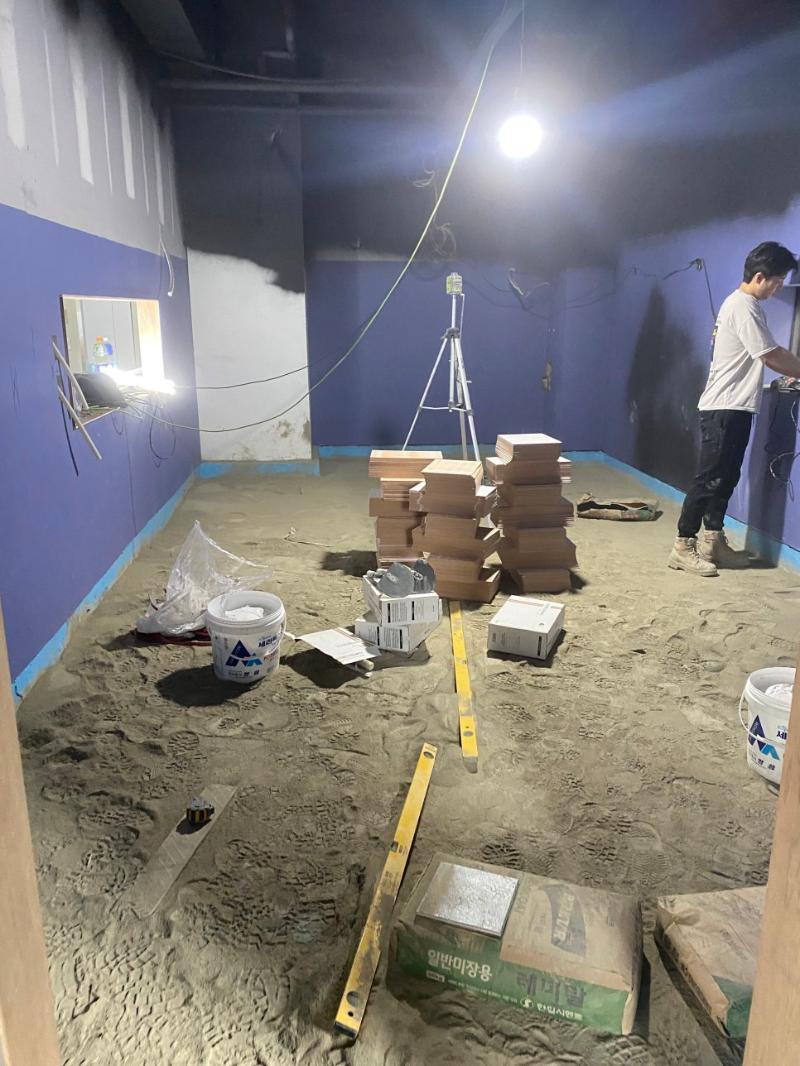타일을 부착하며 도구를 사용하는 시공 장면