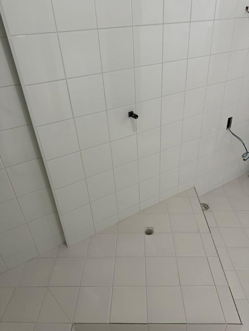 검은색 수도꼭지와 배수구가 보이는 타일 공간