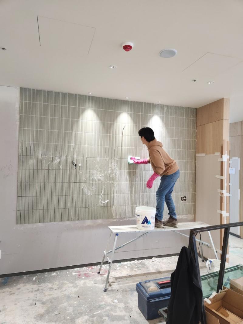 스크래퍼로 수직 타일 벽면을 청소하는 작업 모습