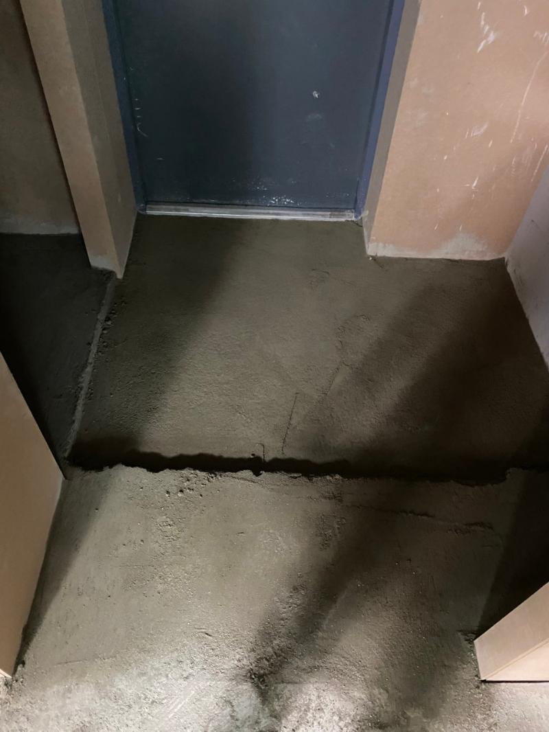 콘크리트 바닥과 어두운 도어가 보이는 복도