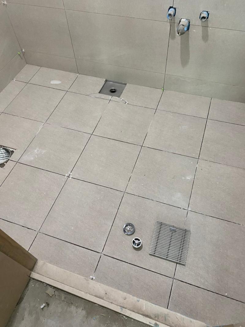 모르타르와 배수판이 보이는 바닥 타일 작업 중