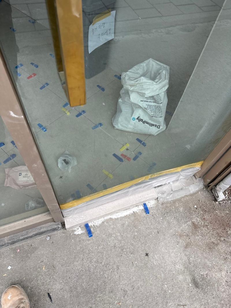 금색 문틀과 타일 바닥, 작업용 테이프가 보이는 공간