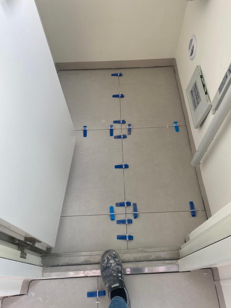 파란색 클립으로 타일 간격을 조정하는 복도 바닥