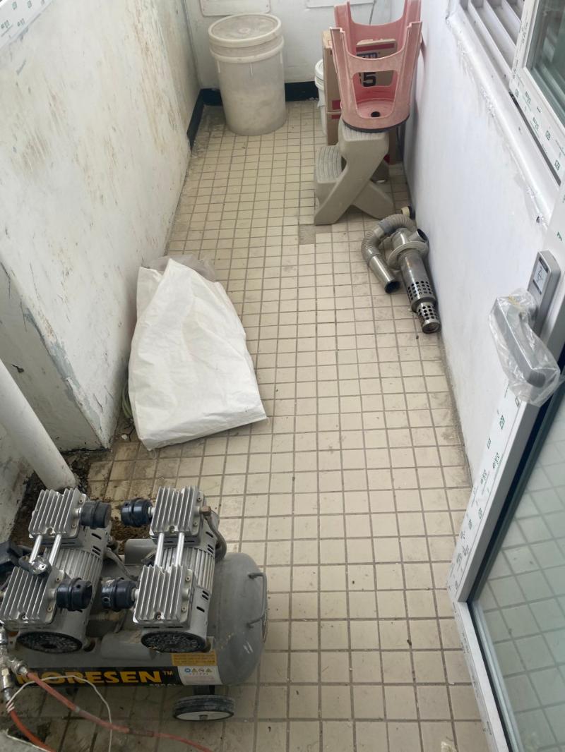 공기 압축기와 금속 파이프가 놓인 창가 작업 공간