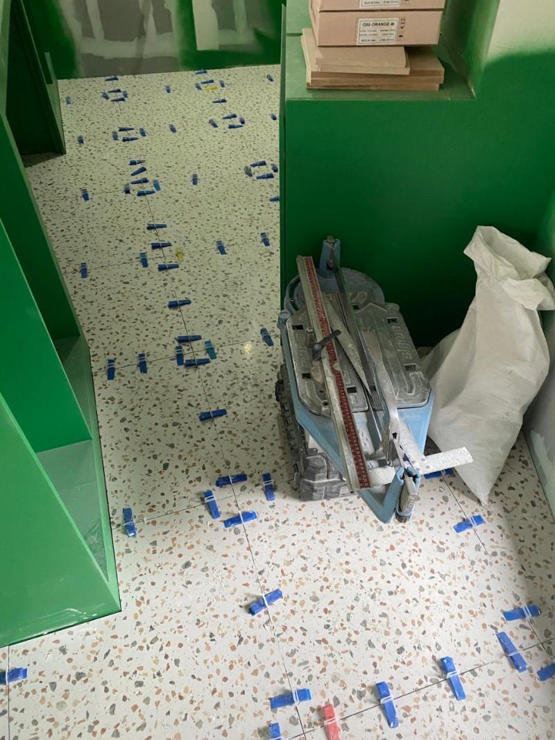 파란색 테이프가 붙은 흰색 타일 바닥과 재단 기구