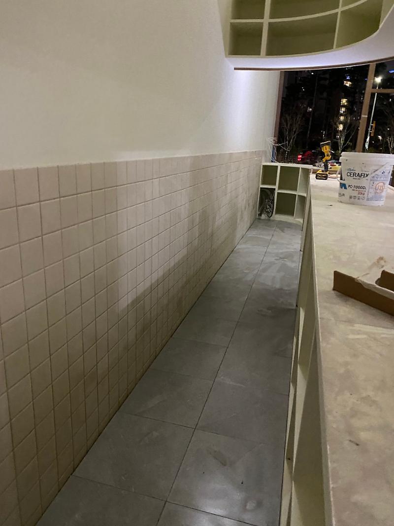 베이지색 벽 타일과 회색 바닥 타일이 배치된 복도