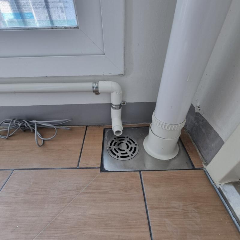 바닥과 벽면에 배치된 흰색 PVC 배관과 금속 배수구