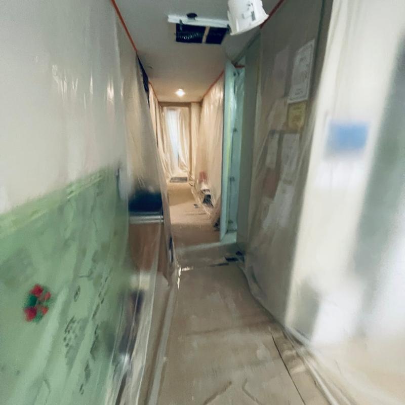 벽면 필름 보양과 천장 조명이 보이는 복도