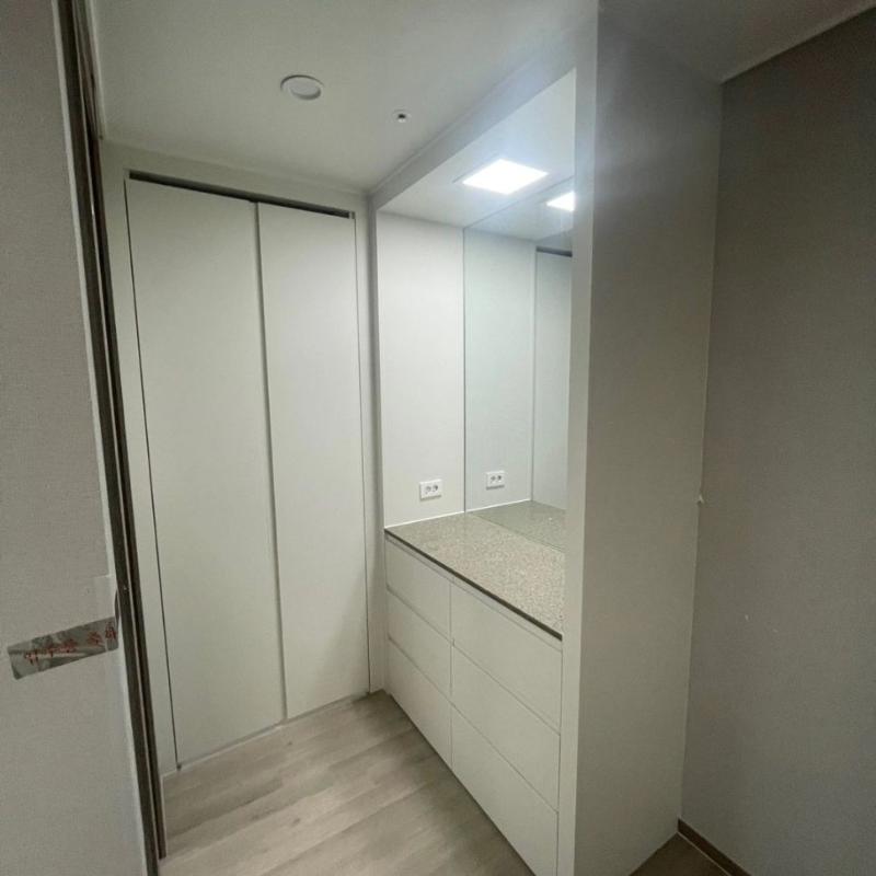 베이지색 상판과 화이트 슬라이딩 도어가 설치된 드레스룸
