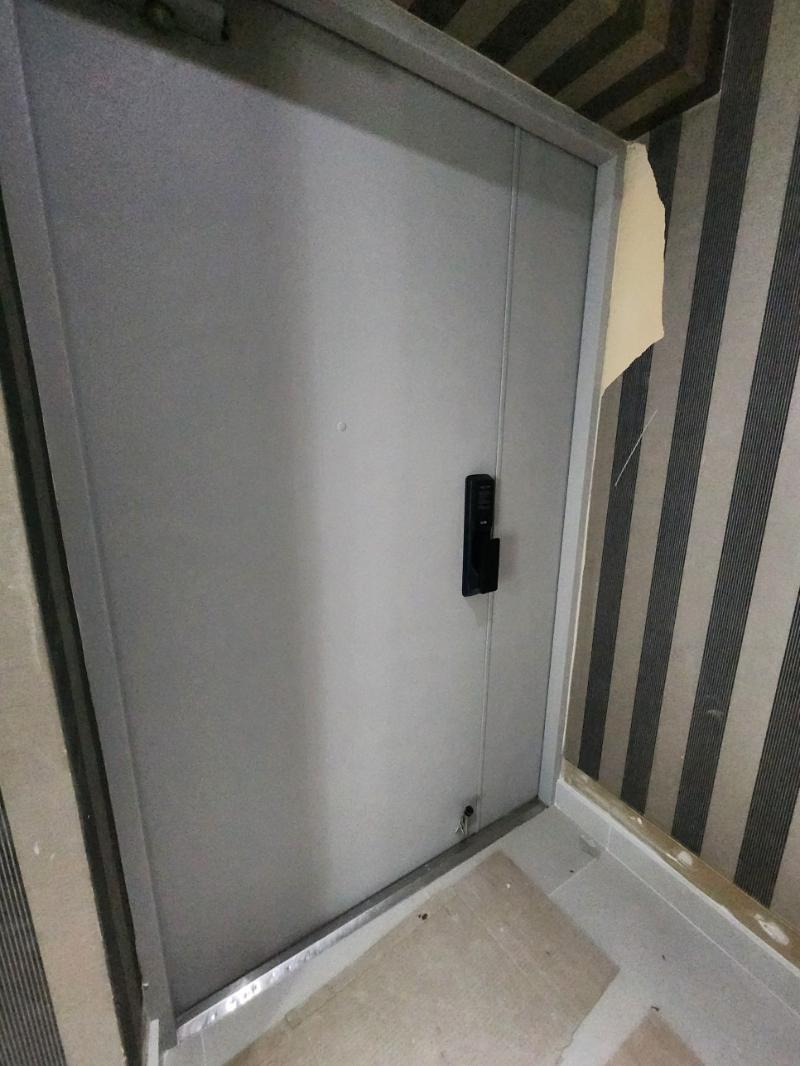 회색 도어와 베이지색 타일이 설치된 현관 공간