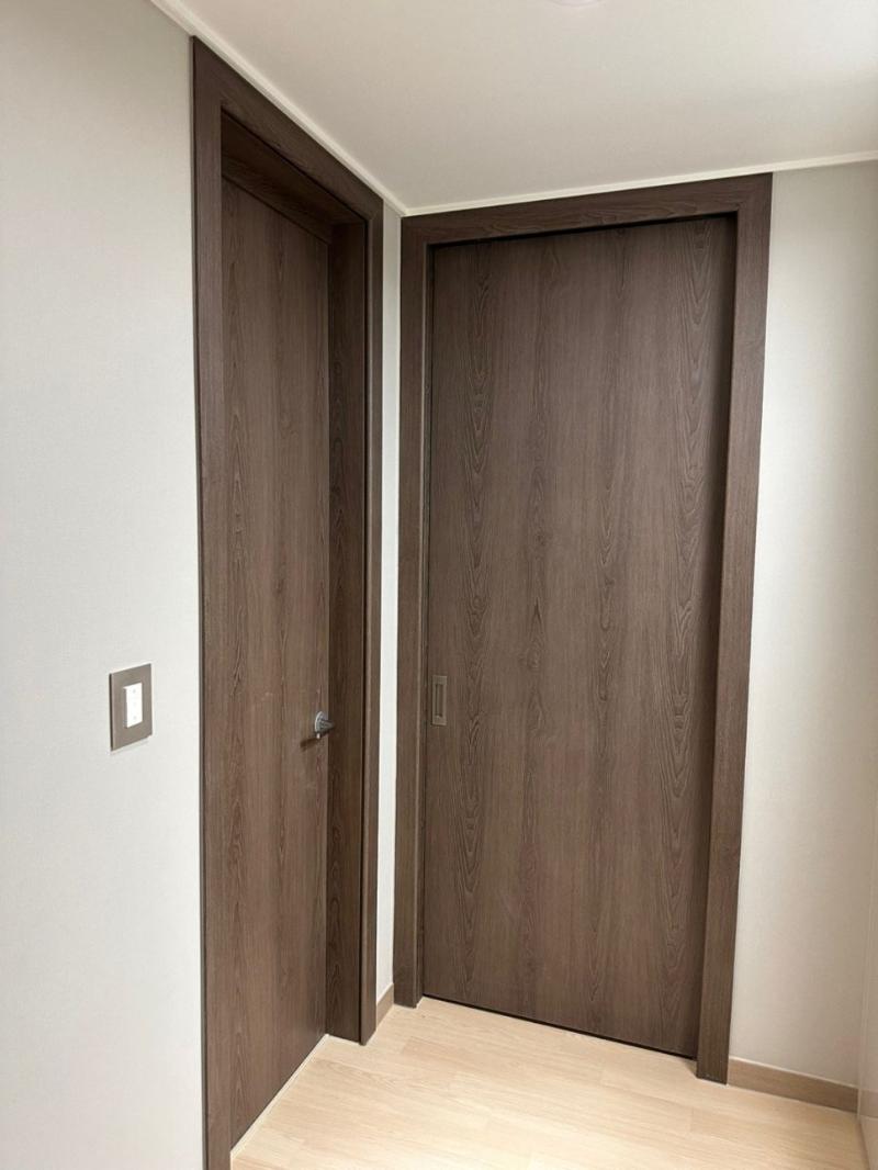흰 벽과 베이지색 바닥재가 적용된 복도의 나무 문들