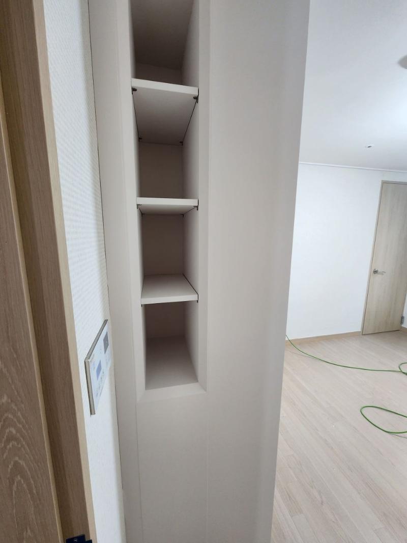 복도 벽면의 3단 수납장과 목재 마루 마감