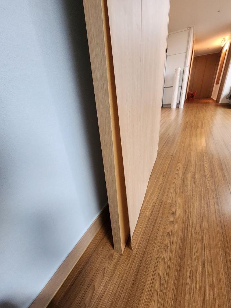 회색 벽면과 목재 도어가 보이는 복도 시공 전
