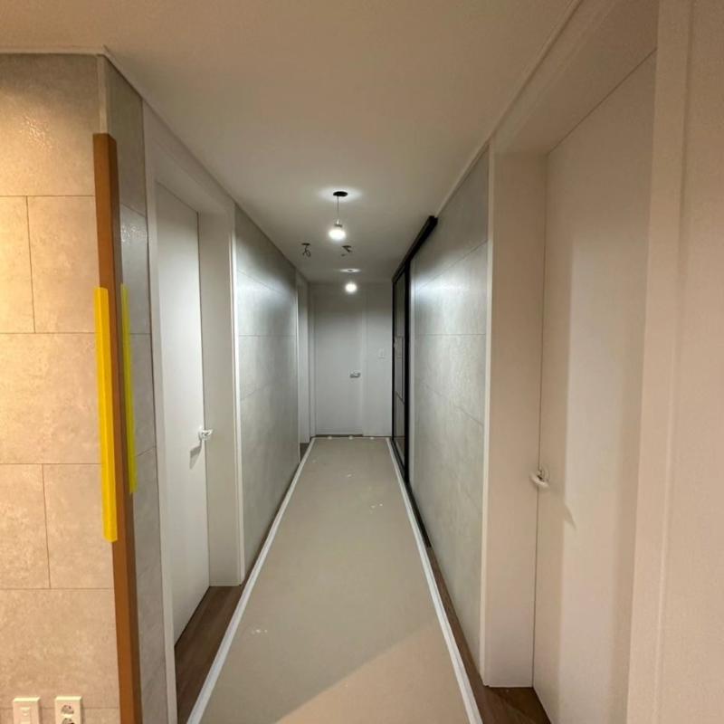 세로 줄무늬 장식과 흰색 문이 보이는 복도