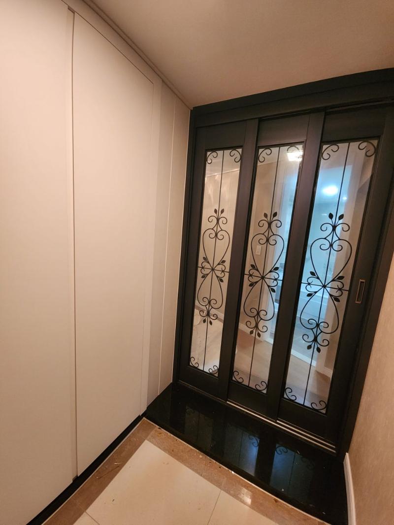 블랙 프레임 유리 도어가 설치된 화이트 톤 복도
