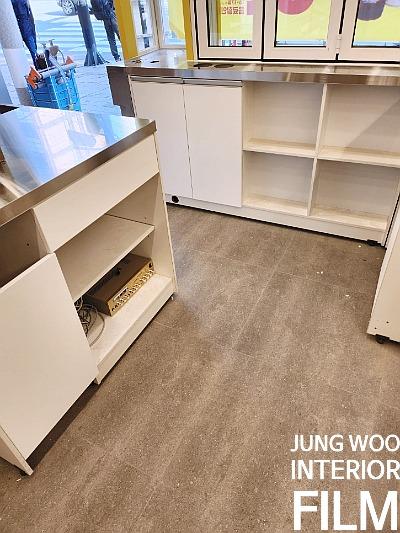 스테인리스 상판과 흰색 수납장이 놓인 베이지색 타일 공간