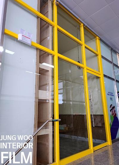 흰색 벽면과 목재 구조물이 인접한 노란 프레임의 창호