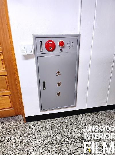 점박이 타일 바닥 위 회색 금속제 소화전 설비