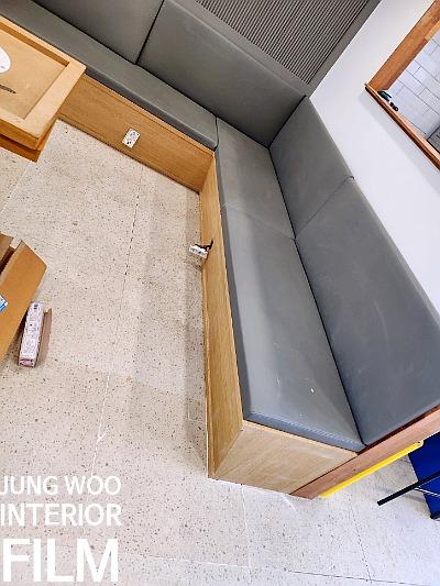 회색 소파와 나무 프레임, 흰색 타일 바닥이 배치된 공간