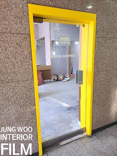 노란 테두리 문 너머로 보이는 카페 브랜드 문구