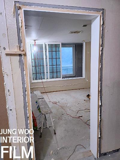 사다리를 이용해 벽면 마감재를 부착 중인 방 내부