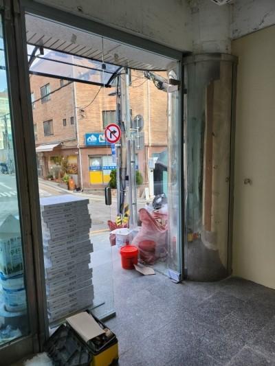 유리문 너머 외부 도로가 보이는 현관 구역