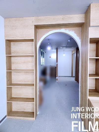 콘크리트 바닥과 나무 질감의 수납장이 보이는 복도 전경