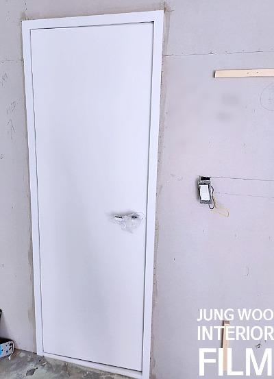 전기 스위치가 부착된 벽면과 설치된 흰색 도어