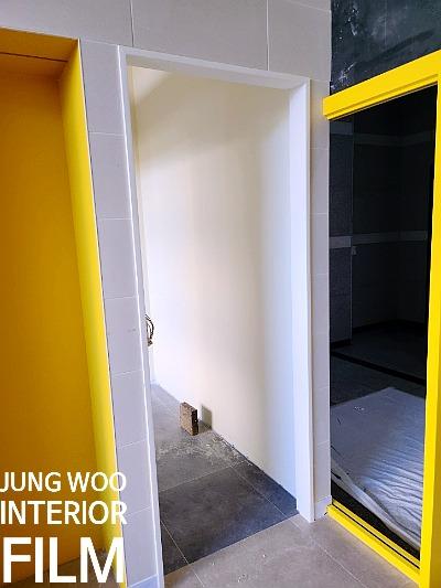 노란색 프레임 문과 회색 타일 바닥의 복도 전경