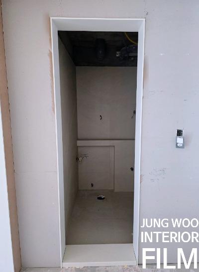 천장 배관이 노출된 상태의 흰색 문틀과 벽면