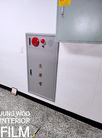 점무늬 타일 바닥과 흰 벽면의 소화기 케이스 및 금속 박스