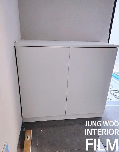 회색 타일 바닥 위 설치된 흰색 수납장