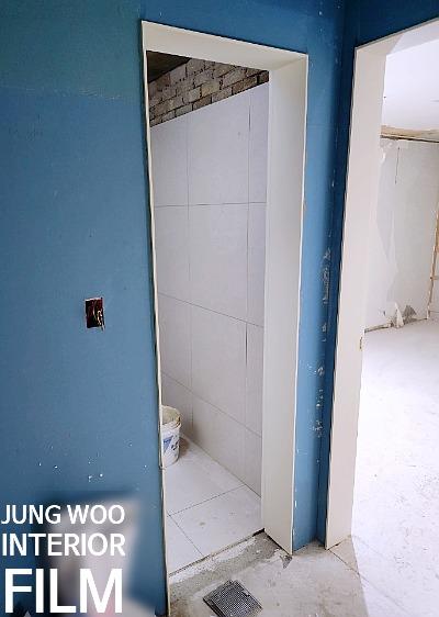 파란 벽면과 흰색 문틀, 바닥 배수구가 보이는 공간