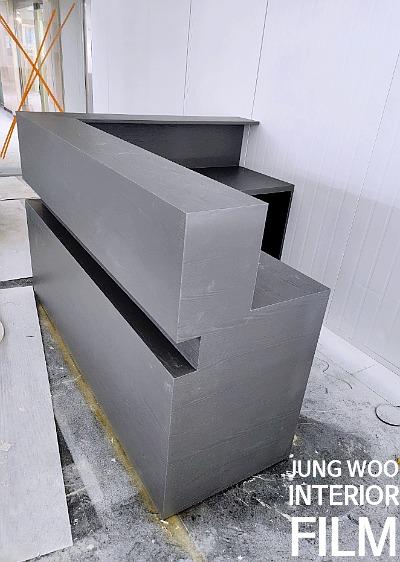 검은색 L자형 구조물과 흰색 패널 벽면