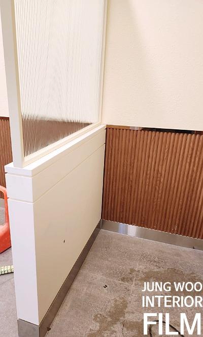 베이지색 벽지와 나무 패널이 나뉜 벽면과 회색 타일 바닥