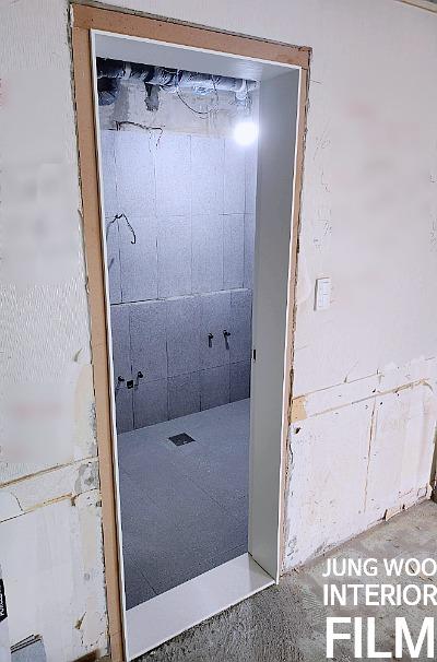 임시 보드로 마감된 문틀과 노출 배관이 보이는 내부
