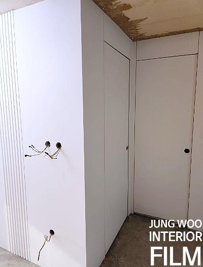 천장이 일부 벗겨진 벽면과 흰색 도어