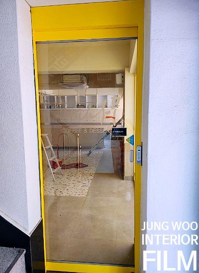 노란색 프레임 너머로 보이는 카페 내부 벽면