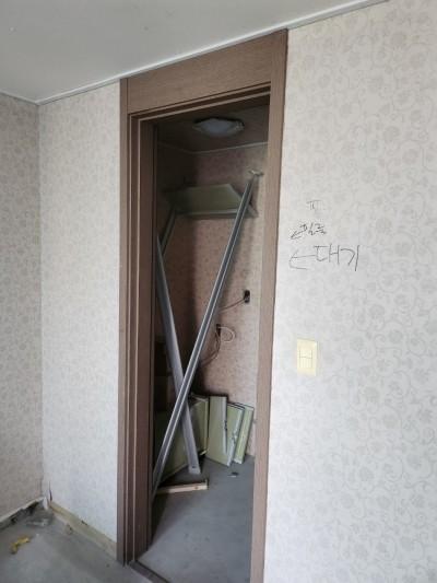 벽지와 문틀, 대기 중인 문짝들이 보이는 공간
