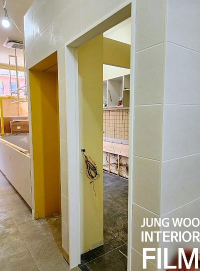 노란색 벽면과 검은색 타일 바닥이 만나는 복도