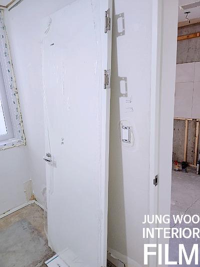마감재가 덧씌워진 벽면과 힌지가 보이는 도어