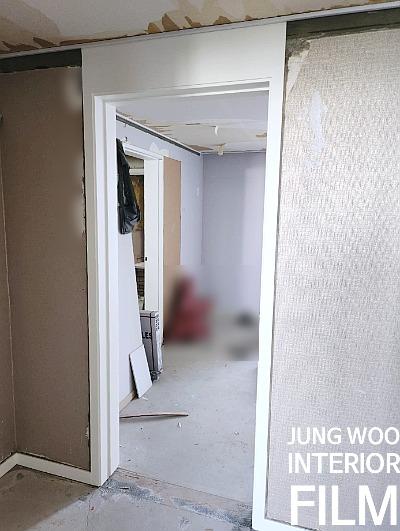 흰색 프레임 문과 벽면 보양재가 보이는 실내
