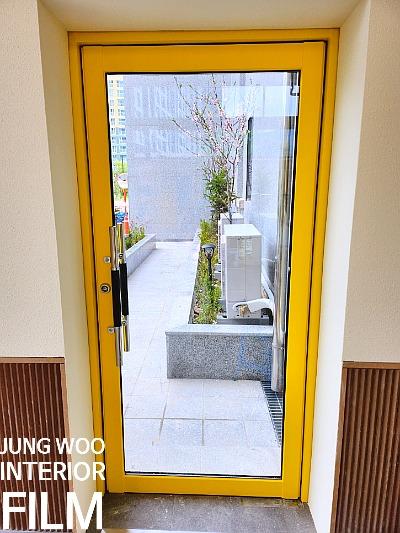 노란색 도어가 설치된 현관과 외부 식물 공간