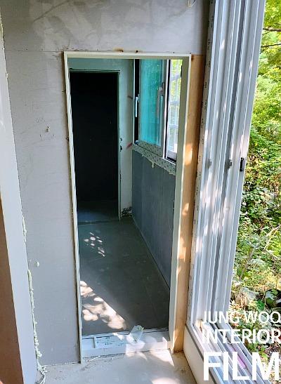 흰색 프레임의 문과 창호가 보이는 공사 중인 복도