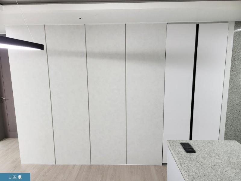흰색 수납장과 석재 상판 카운터가 배치된 주방 모습