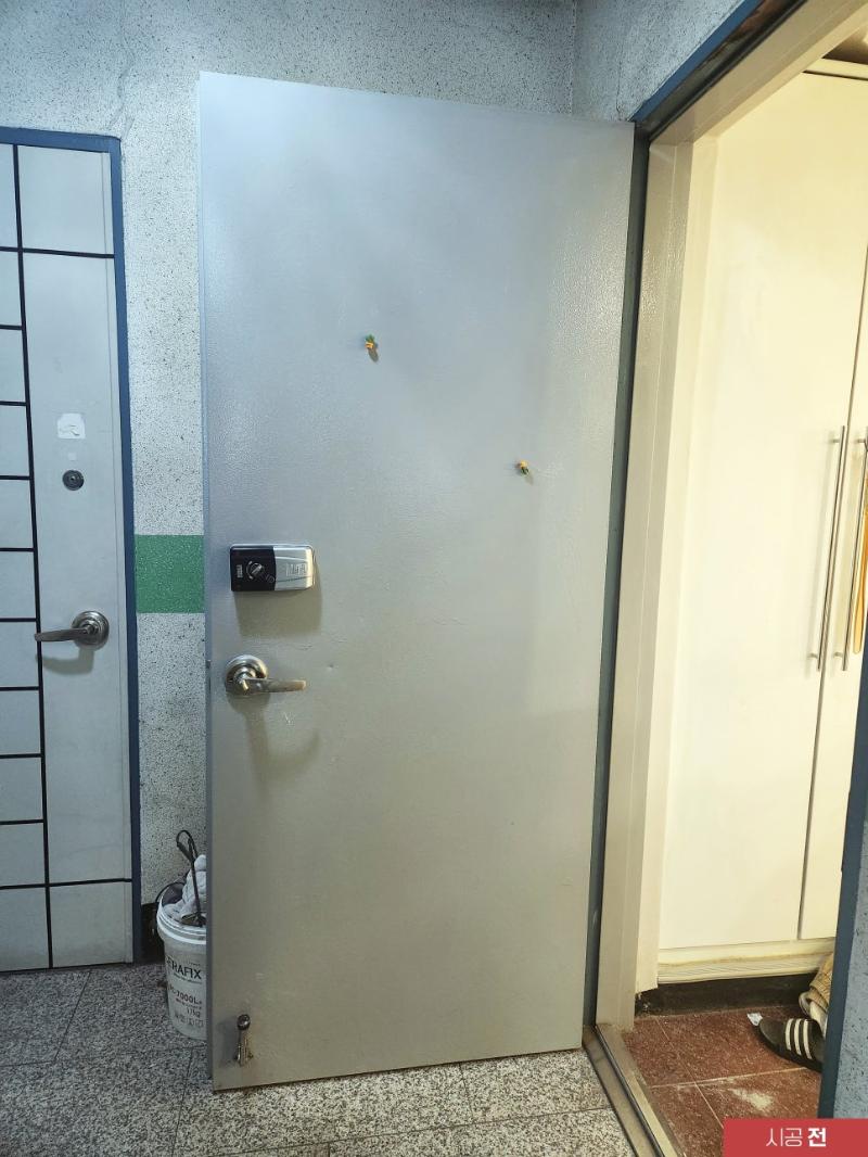 흰색 도어가 설치된 시공 전 현관 공간