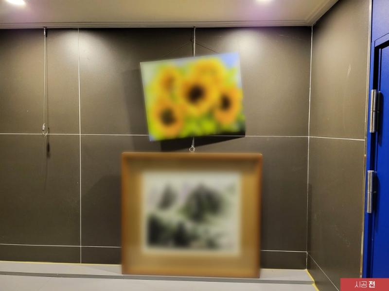회색 타일 벽면과 파란색 문이 보이는 시공 전 모습