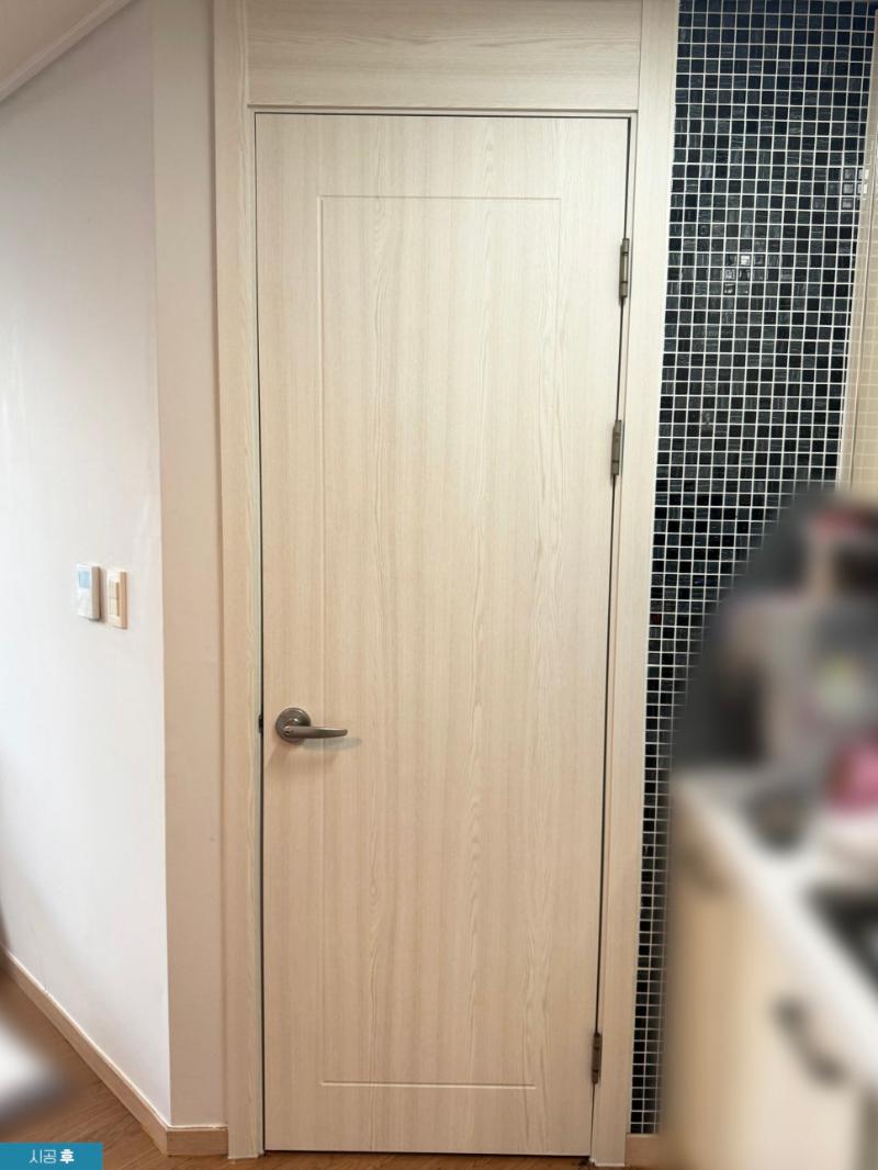 베이지색 도어와 검은색 모자이크 타일이 어우러진 복도