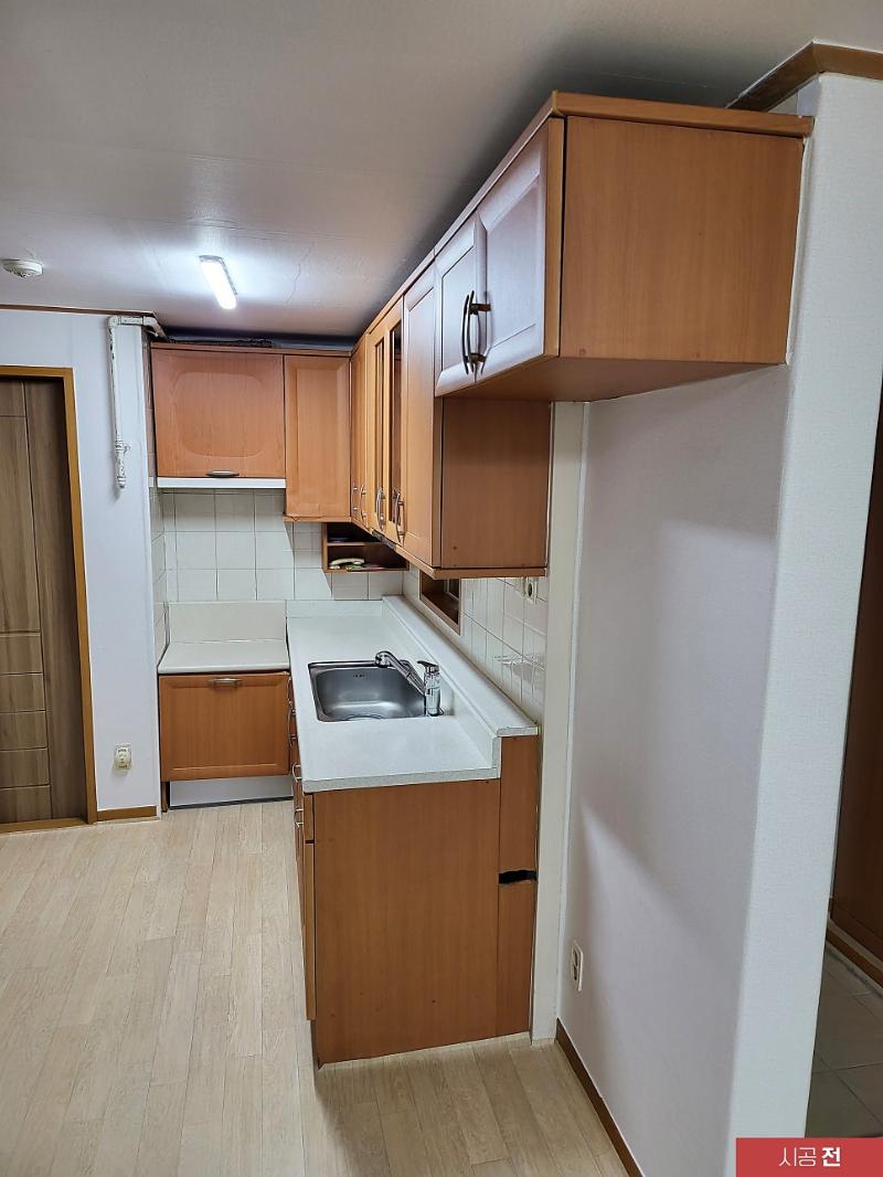 베이지색 목재 가구와 흰색 상판이 보이는 주방