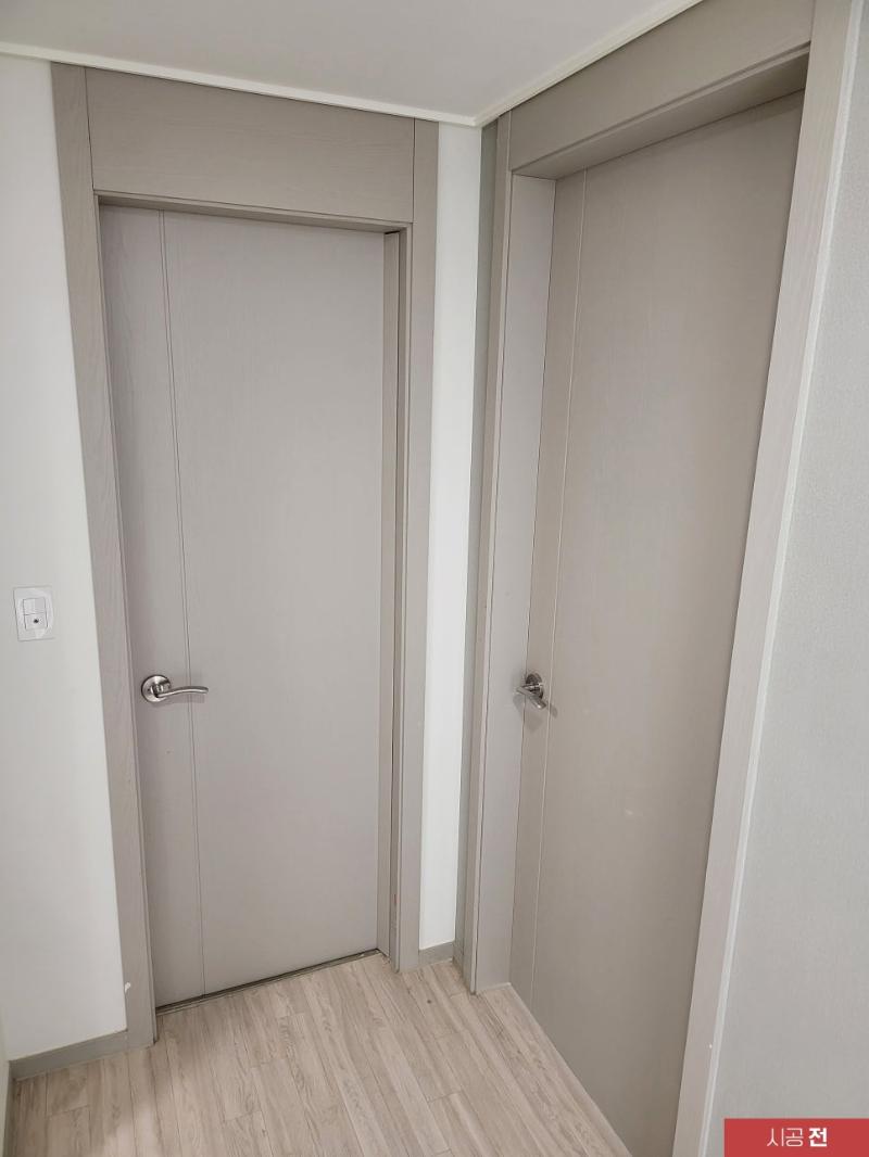 흰 벽과 베이지색 문들이 배치된 시공 전 복도 전경